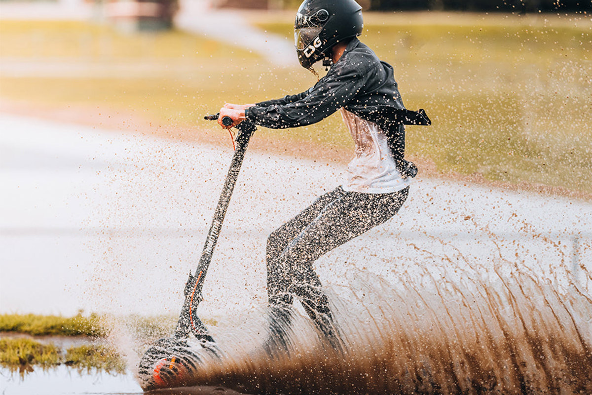 Electric scooter Inmotion climber man riding in water Man riding Inmotion Climber electric scooter through water and mud, wearing helmet and safety gear – showcasing off-road capability and waterproof design