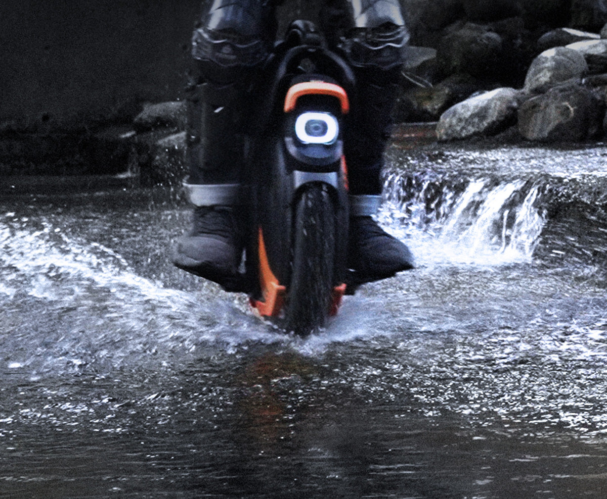 Inmotion V11Y electric unicycle riding through water, showcasing its IPX6 water-resistant design.