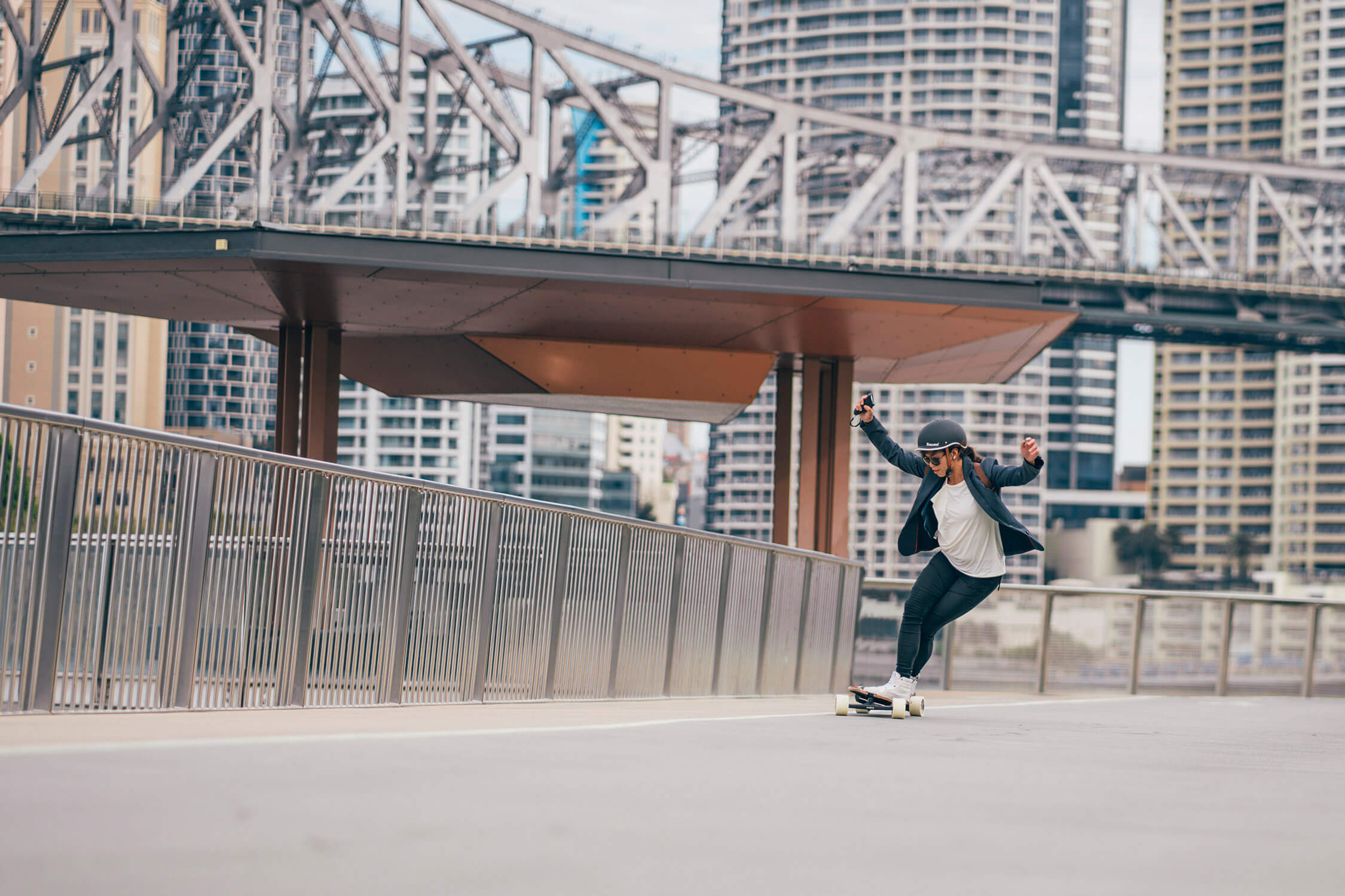 Rider carving with the Evolve Hadean Bamboo Street electric skateboard in an urban setting
