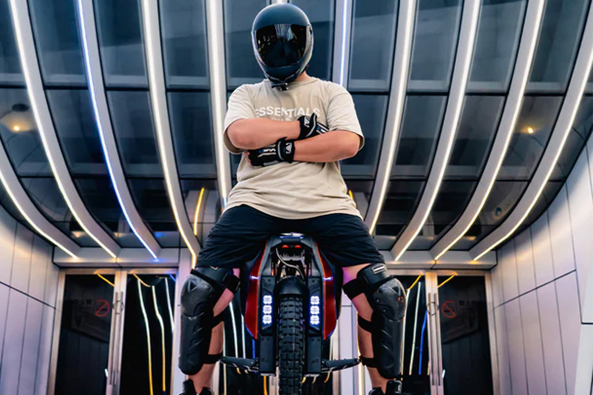 Man in full gear sitting on Kingsong KS S19 electric unicycle in front of futuristic building lights