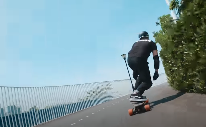 Review video thumbnail of Electric skateboard Exway Flex ER Hub where man is riding the skateboard uphill viewed from the back.