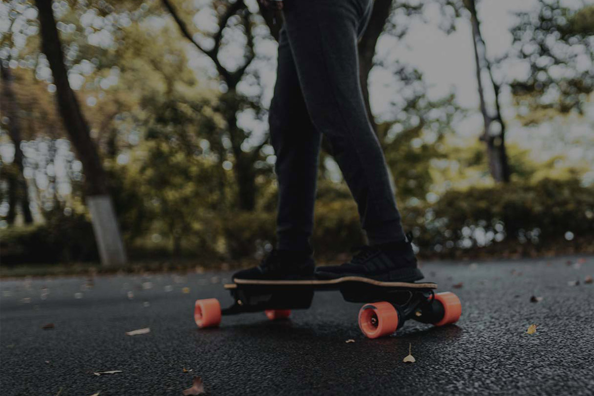 Electric skateboard Exway Flex ER Hub man riding Man riding Electric skateboard Exway Flex ER Hub viewed from the side and riders legs and board are visible.