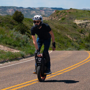Electric unicycle Inmotion V13 Challenger being ridden at high speed on a curved highway, showcasing stability and road performance.