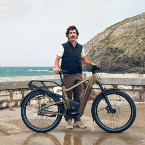 Rider posing with a bronze Riese & Müller Delite electric bike, a premium touring e-bike for adventure and performance