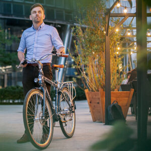 Man standing with Oolter Eke electric city bike next to a modern café terrace