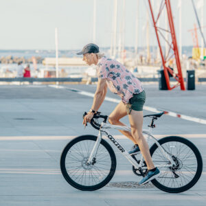Man riding white Oolter Torm S electric bike at a modern seaside port during summer