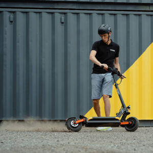 GPAD electric scooter rider performing a controlled slide on gravel surface