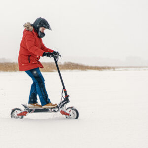 Person riding dual-motor GPAD Storm electric scooter in snowy winter conditions
