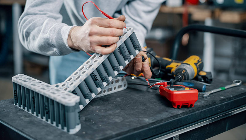 A banner showing a Voltride technician measuring the voltage of a battery