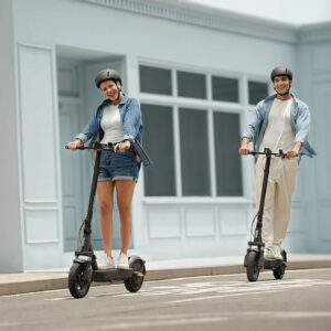 Young couple riding Xiaomi electric scooters on a city street wearing helmets