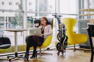 Woman sitting next to the Stigo electric bike in the office or cafeteria.