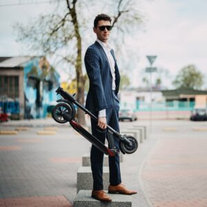 Man carrying folded E-TWOW S2 Booster V electric scooter, showcasing lightweight and portable design.