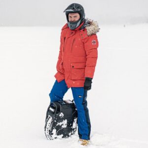 Man standing in snow with the Veteran Sherman Max electric unicycle wearing a full face helmet.