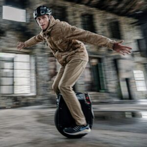 Man riding the Veteran Sherman Max electric unicycle in an old building wearing a helmet.