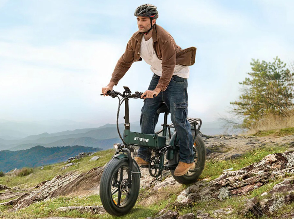 Man riding the green Engwe Engine PRO 2.0 electric bicycle in an upright position on a mountain wearing a helmet and demonstrating the bike's braking mechanism.
