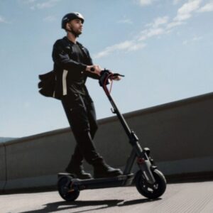 Man riding the Segway-Ninebot MAX G3 electric scooter on the city street wearing a helmet.