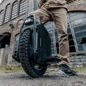 Man standing with the Veteran Sherman Max electric unicycle in front of an old building.