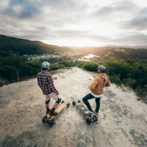 Men standing on a mountain with Evolve Electric Skateboards wearing helmets.