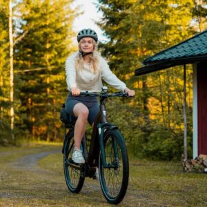 Young woman riding a Tunturi eHybrid electric bicycle in the forest or country side wearing a helmet.