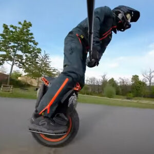 Close-up view of a man riding the Begode Extreme 50s electric unicycle on asphalt wearing protective gear.