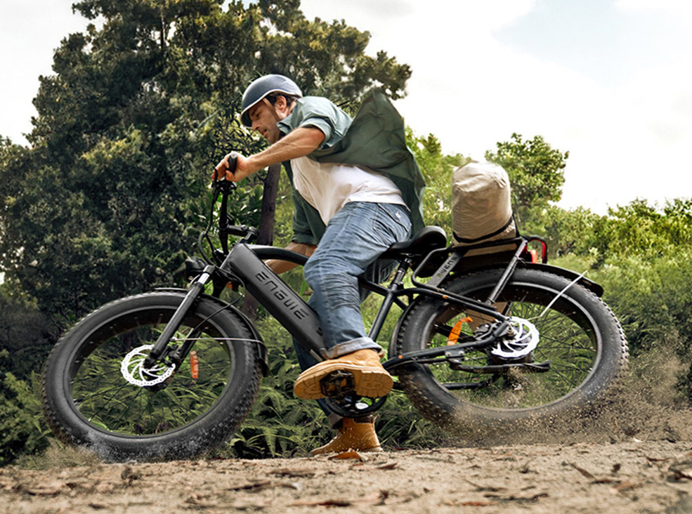 Engwe E26 braking A rider in outdoor gear skids through a dirt trail on a fat-tire Engwe E26 electric bike, kicking up dust while leaning into the turn.