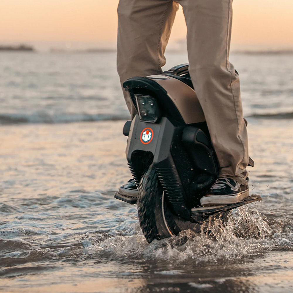 Rider on the Inmotion V12S electric unicycle splashing through water demonstrating the wheel's water resistance.