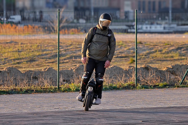 Person riding an electric unicycle on a paved path wearing helmet and protective gear