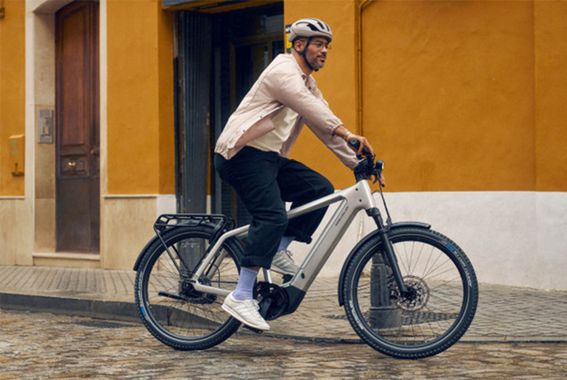 Man riding the Riese Müller Charger5 Vario T electric bike on the city street wearing a helmet.
