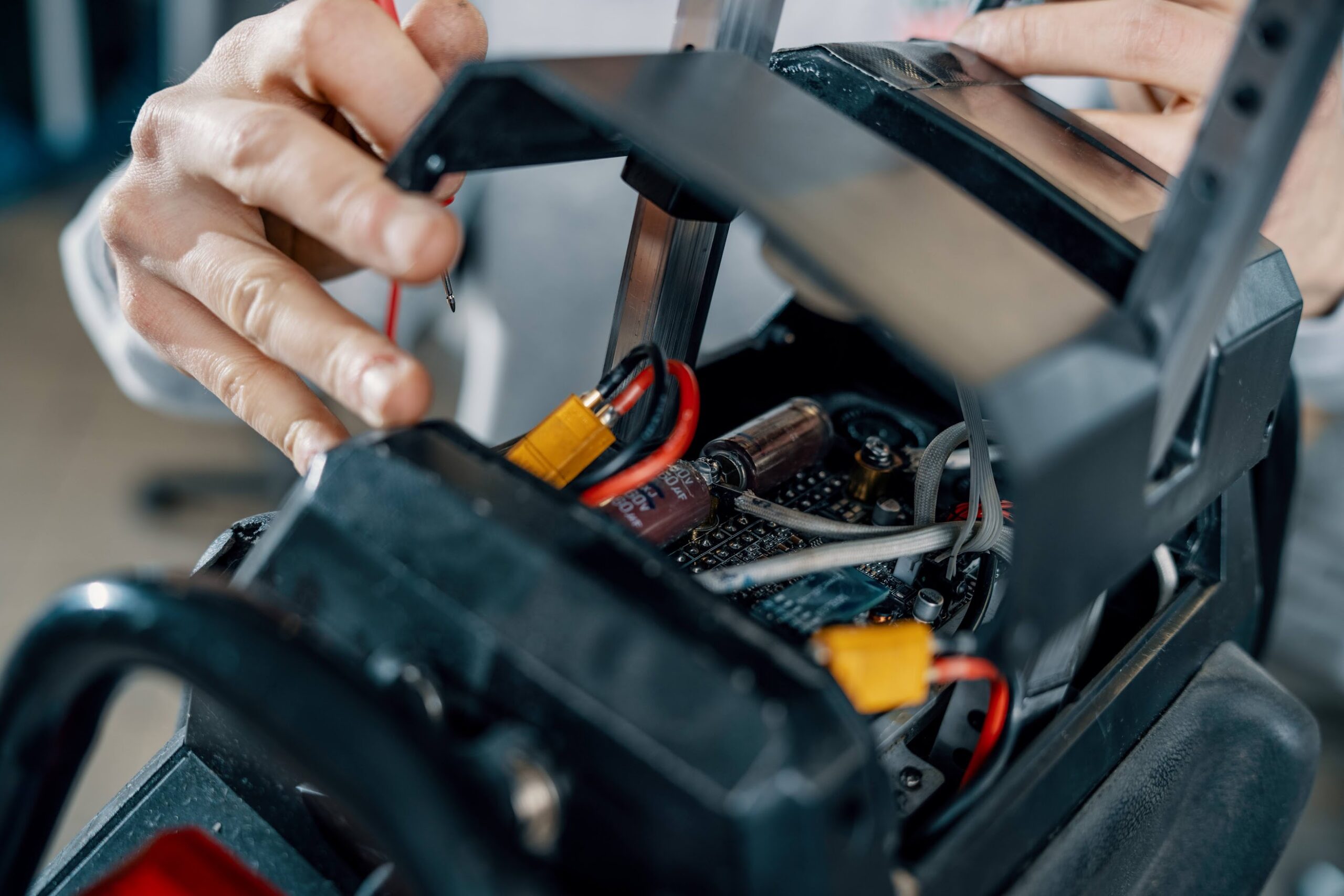 Close-up of a technician working on the internal wiring and components of an electric unicycle